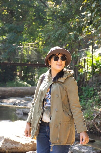 A person wearing a wide-brimmed hat, long-sleeved UPF shirt, and sunglasses, enjoying an outdoor activity like hiking, demonstrating comprehensive sun protection.