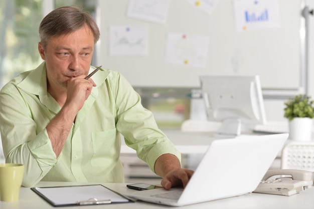 A person sitting at a desk, looking at financial documents and a laptop, with a thoughtful expression, symbolizing proactive financial planning and analysis.