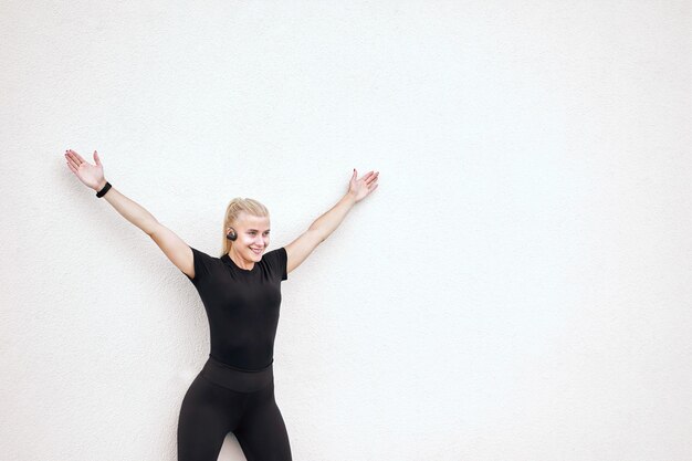 A senior woman with silver hair performing a wall push-up, demonstrating good form and engagement, smiling slightly.