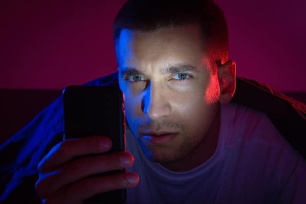 A person's eye partially covered by a smartphone screen emitting a vibrant blue light in a dark room.